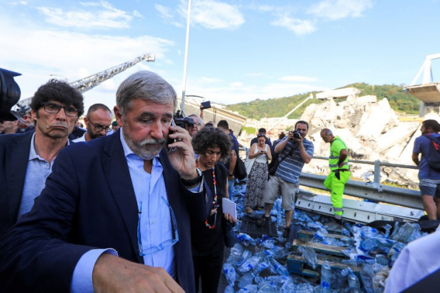 Mayor of Genoa Marco Bucci speaks on a mobile as he walks at the site where the Morandi motorway bridge collapsed. Photo: Valery Hache / AFP